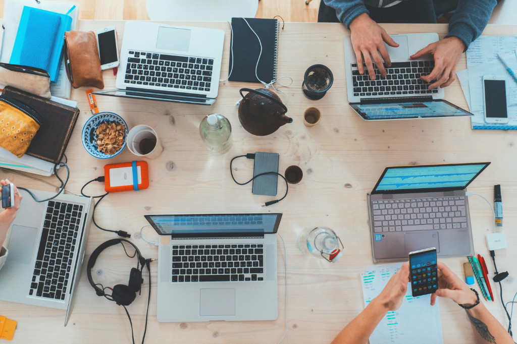 Tisch wo mehrere Laptops drauf sind und Personen daran arbeiten
